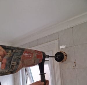 Electrician drill a new bathroom extractor fan Faraday Engineering 