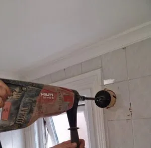 Electrician drill a new bathroom extractor fan Faraday Engineering 