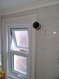 Drilling a new hole for bathroom extractor fan installation by Faraday Engineering in London